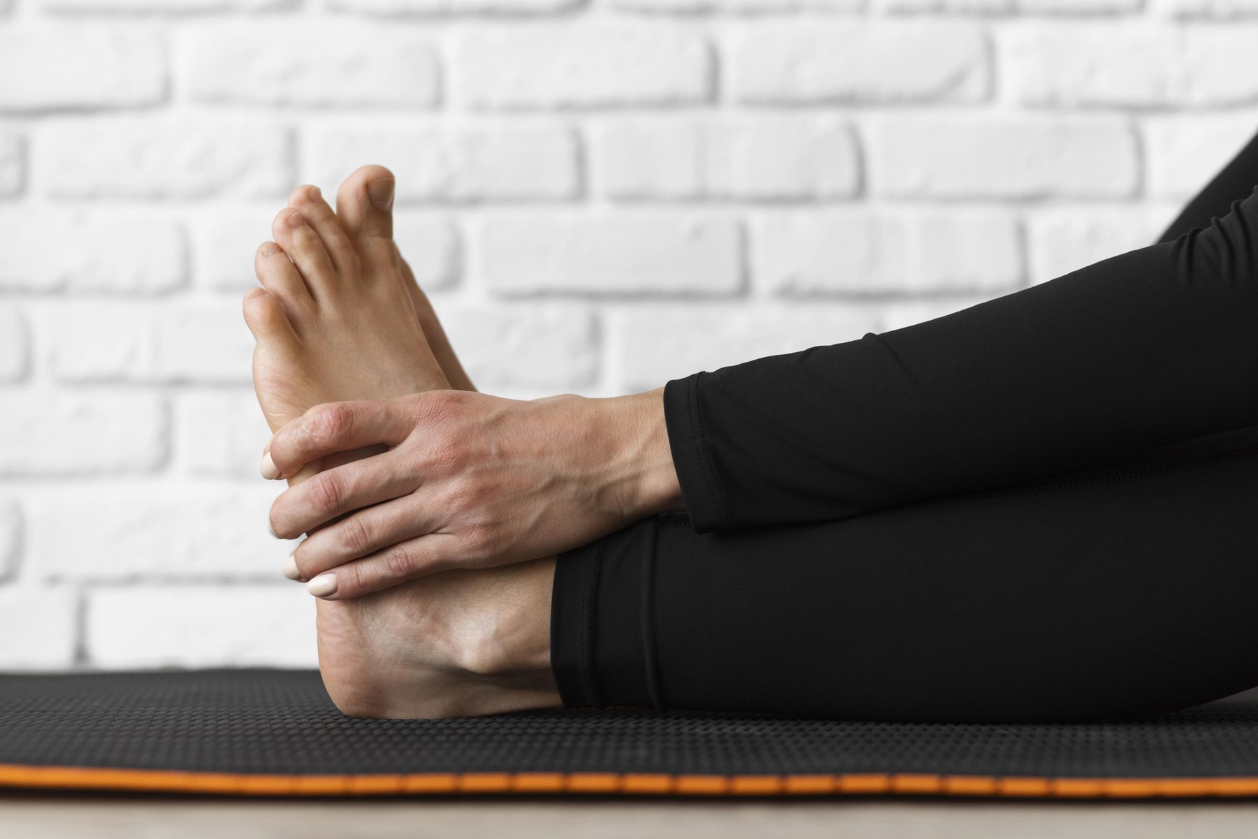 person stretching and holding their foot